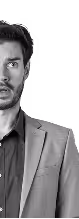 Black and white portrait of a man in a blazer and shirt looking directly at the camera.